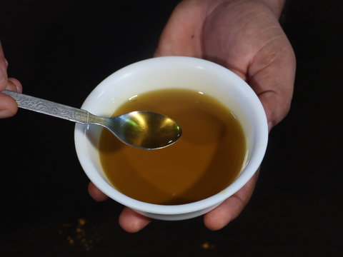 Mustard Oil in White Bowl on Wooden Background,Mustard Oil in White Bowl on Hand, Closeup of Mustard oil in Hand,