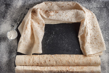 Lavash bread on black background, top view. Traditional bread in Middle East and Central Asia. It can be used for wraps, rollups, crackers and pizza.