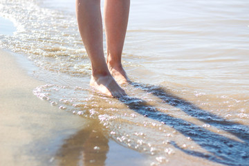 Girl's feet on the beach. Sea waves and legs