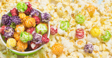 a sweet, colorful popcorn lies in a bucket and is scattered on the table