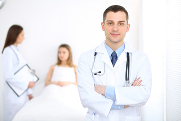 Fototapeta premium Medicine doctor standing and smiling on the background with patient in the bed