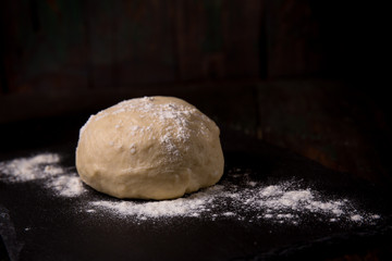 Fototapeta na wymiar Dough with flour on a black board