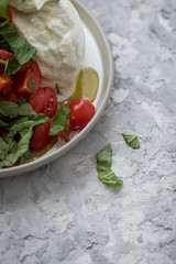 Büffelmozzarella Kugel mit Tomaten, Basilikum, Olivenöl und weißen Balsamico auf Teller