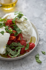 Büffelmozzarella Kugel mit Tomaten, Basilikum, Olivenöl und weißen Balsamico auf Teller