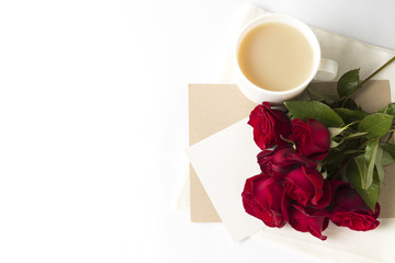 Bouquet of red roses and an envelope with a note, a white cup of