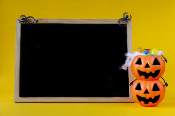 Halloween Jack o Lantern bucket and blank chalkboard on yellow background