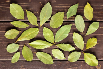 Lot of whole dry olive green bay laurel leaves flatlay on brown wood