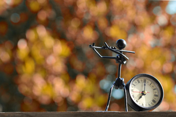 Retro clock with a unique violin statue and autumn bokeh background
