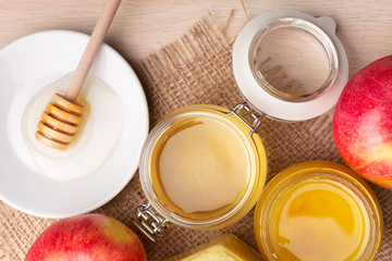 Jewish holiday Rosh Hashanah background with honey and apples on wooden table.