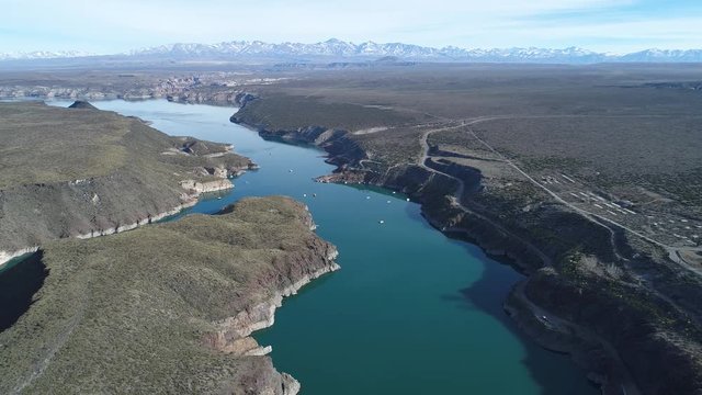 Aerial drone scene of Agua de Toro lake at San Rafael, Mendoza, Cuyo Argentina. Camera moving backwards at high altitude with complete view of lake and high snowy plata mountains at background