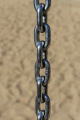 Six chain links with blurry sand in the background