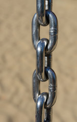 Three chain links with blurry sand in the background