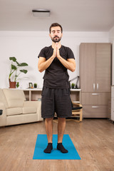 Fit man practicing yoga in the living room of his house