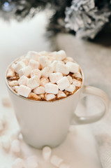 Hot cocoa with marshmallow, cinnamon, warm cozy light plaid and Christmas tree branches on white table.