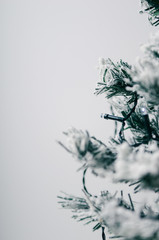 Artificial fir-tree with snow on a white background with an electric garland. Toned photo.