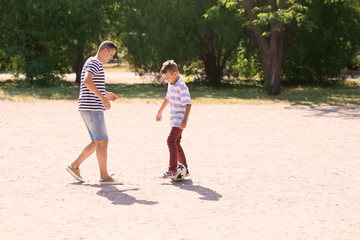 Little boy with his dad playing football outdoors
