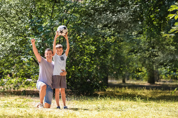 Little boy and his dad with soccer ball outdoors