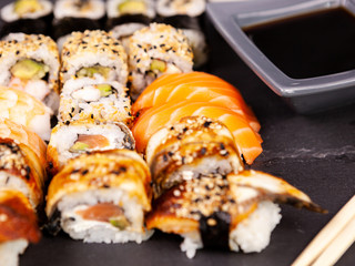Lot mix variety of sushi rolls on black stone background in studio photo