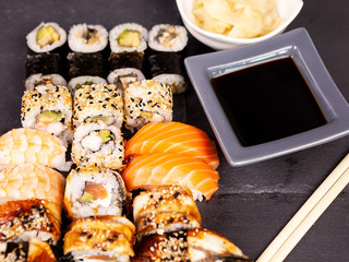 Lot mix variety of sushi rolls on black stone background in studio photo