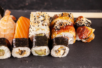 Variety mix of sushi rolls on black background in studio photo