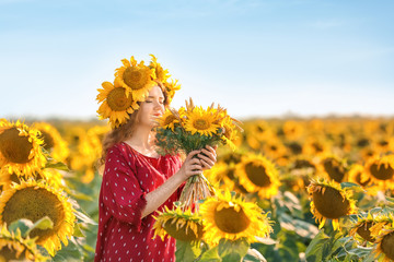 Beautiful redhead woman in sunflower field on sunny day