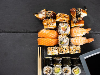 Top view of mix variety of sushi rolls on black background in studio
