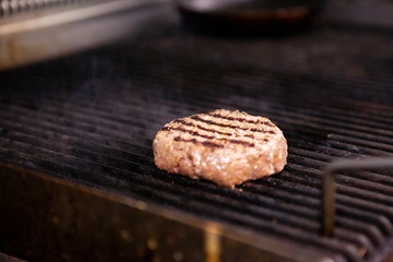 Chef is grilling a meat burger on the grill. Fast cuisine