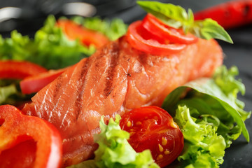 Tasty salmon with salad on plate, closeup