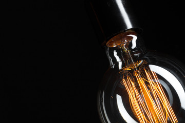 A classic Edison light bulb on dark background with space for text