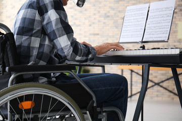 Young musician in wheelchair playing synthesizer at home