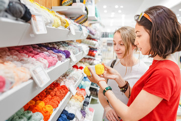 Woman choosing yarn and wool balls for purchase in craft shop