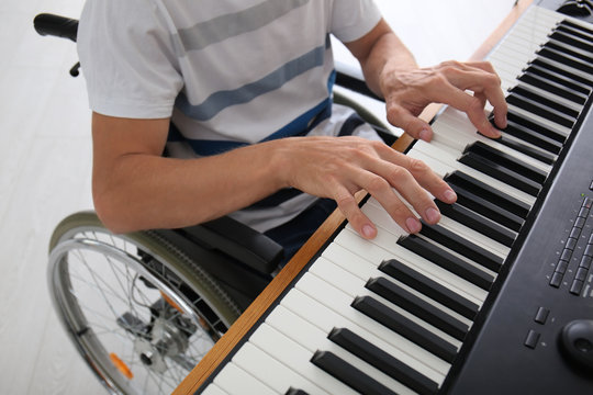 Young musician in wheelchair playing synthesizer at home