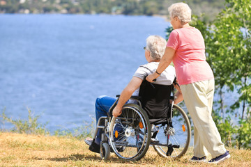 Senior man in wheelchair and his wife near river