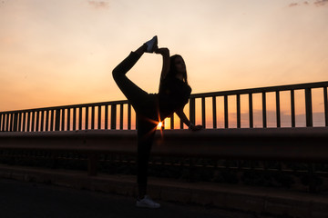 beautiful young brunette girl posing a road in the middle of the field at sunset, ballet, silhouette