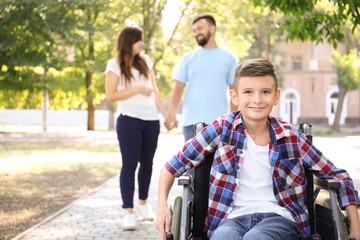 Teenage boy in wheelchair with his family walking outdoors
