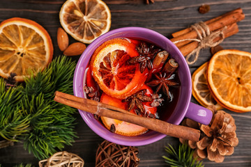 Cup of delicious mulled wine on wooden table