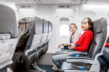Fototapeta premium Happy Girlfriends traveling by plane together, air flight passengers