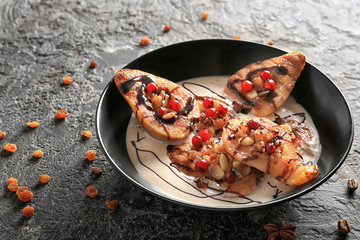 Bowl with baked pears, cream and chocolate syrup on dark table