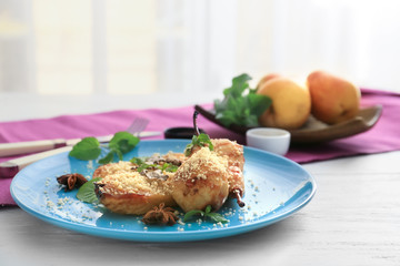 Plate with baked pears on light wooden table