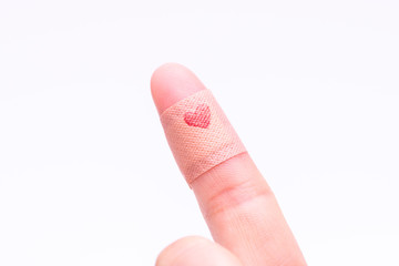 A band aid on finger with red heart.