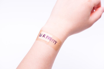 Self-confident concept: A band aid on wrist with hand writing "You are pretty".