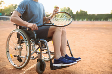Young man in wheelchair playing tennis on court
