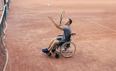 Young man in wheelchair playing tennis on court