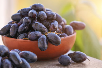 Bowl with sweet grapes on wooden table outdoors