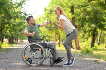 Man in wheelchair with beautiful woman dancing outdoors