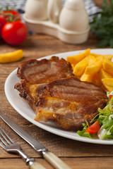 Grilled pork neck served with French fries and salad.