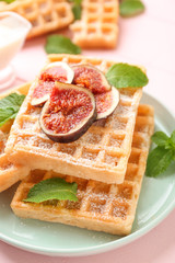 Delicious waffles with fig slices on plate