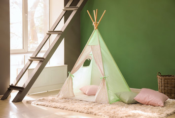 Cozy play tent for kids near color wall © Pixel-Shot