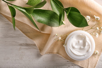 Jar with body cream on white wooden table, top view