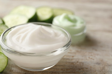 Bowl with cucumber body cream on wooden table, closeup